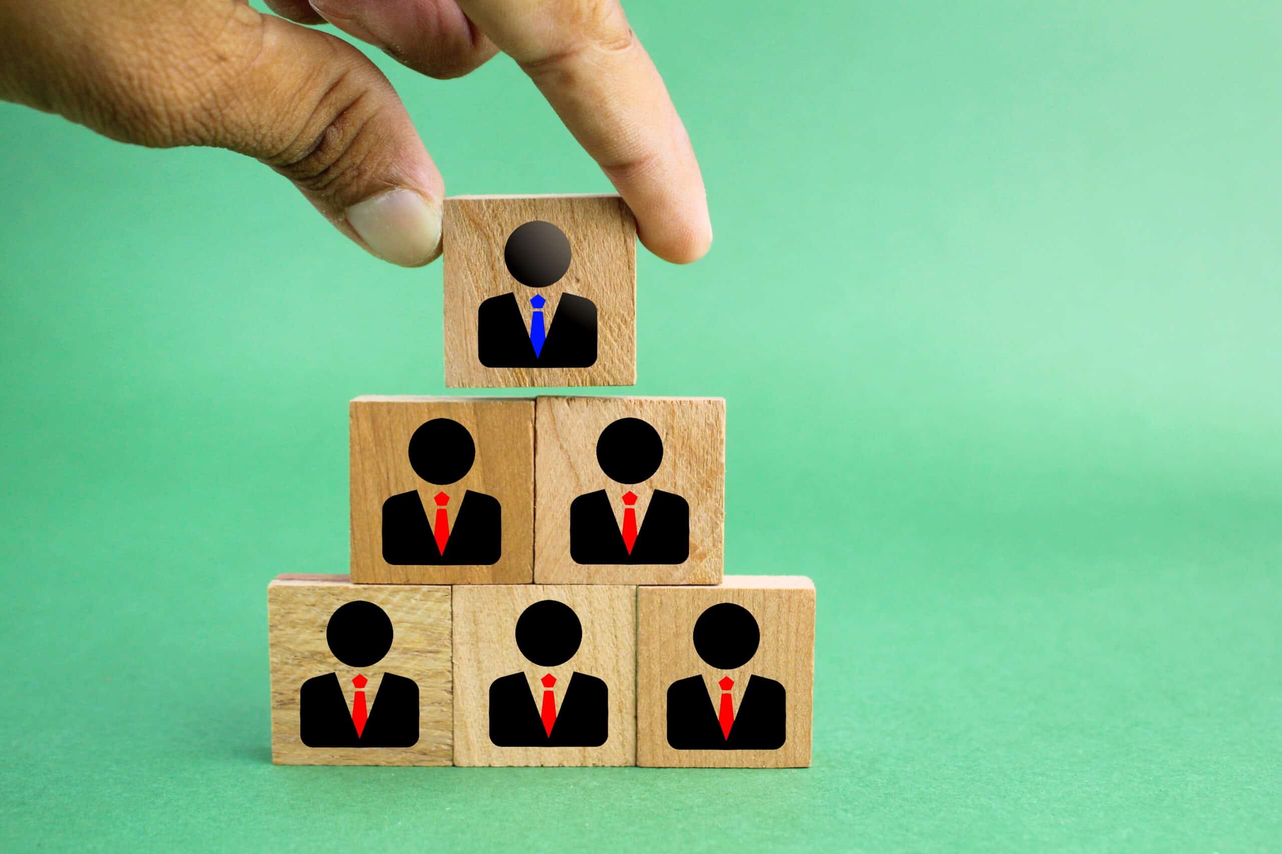 Hand stacking wooden blocks with professional icons representing HR team members.